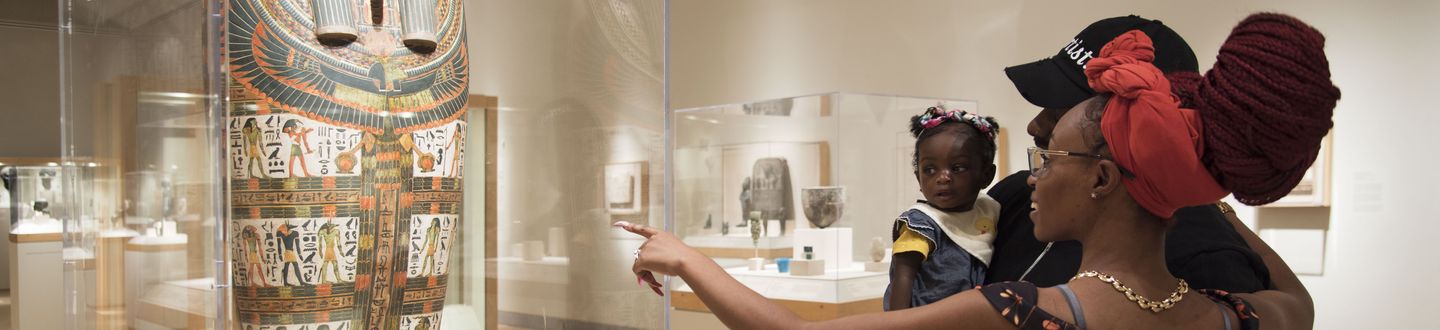 A family with a baby looking at Egyptian art